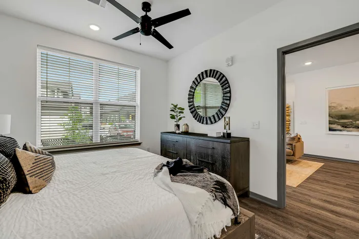 Bright and modern bedroom featuring a cozy bed, elegant decor, and sunlit window, seamlessly opens into a welcoming living space.