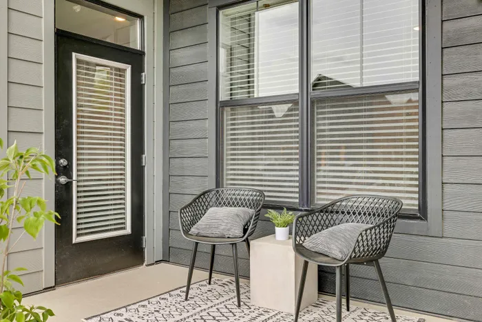 Charming apartment patio featuring two sleek chairs, a cozy plant arrangement, and elegant outdoor decor.