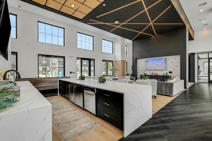 Luxurious modern living area with high ceilings, expansive windows, and sleek marble countertops.
