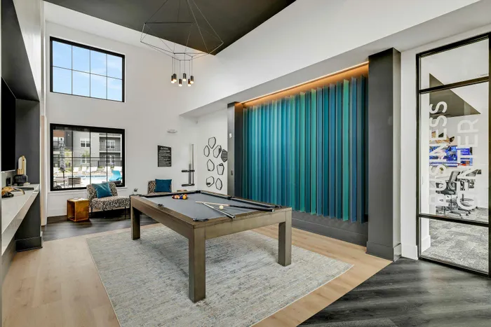 Modern recreation room featuring a pool table, cozy seating, and vibrant blue accent wall, ideal for relaxation and entertainment.