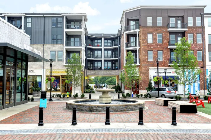 Vibrant urban plaza with modern apartment buildings, elegant brick architecture, charming boutique shops, and a stunning central fountain.