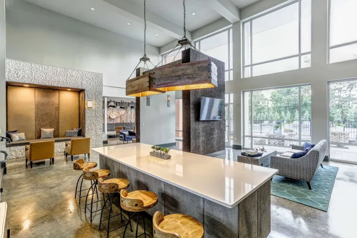 Luxurious apartment common area with a high ceiling, expansive windows, modern seating, and elegant wooden accents.