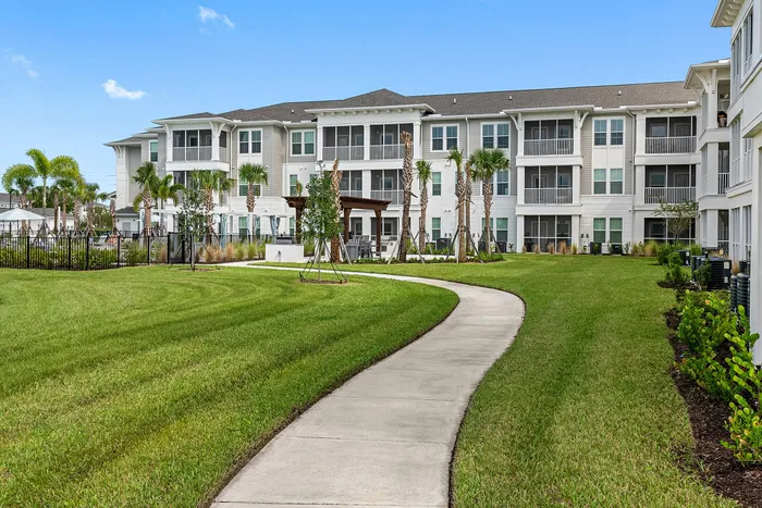 Elegant apartment complex with modern architecture, surrounded by lush greenery and a scenic walkway for a serene living experience.