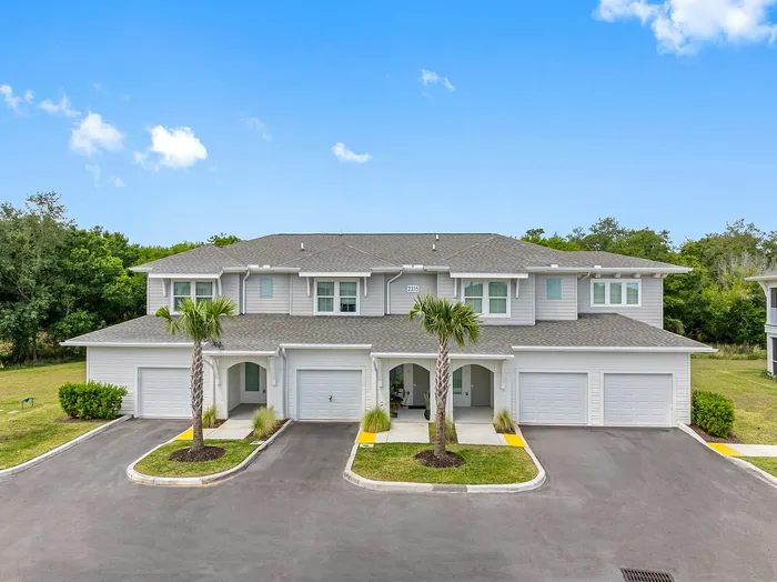 Charming suburban apartment complex with modern design, lush greenery, and palm trees, perfect for serene living.