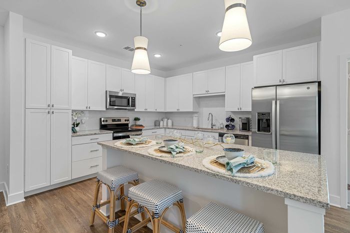 Modern kitchen featuring sleek white cabinetry, stainless steel appliances, and a spacious island with stylish bar seating for a perfect blend of functionality and elegance.