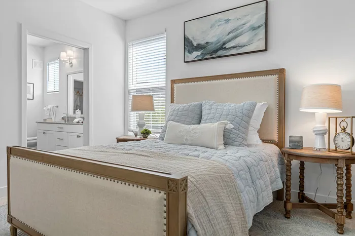 Charming bedroom with elegant decor featuring a cozy bed, stylish bedside tables, soft lighting, and tranquil artwork, adjacent to a modern bathroom.