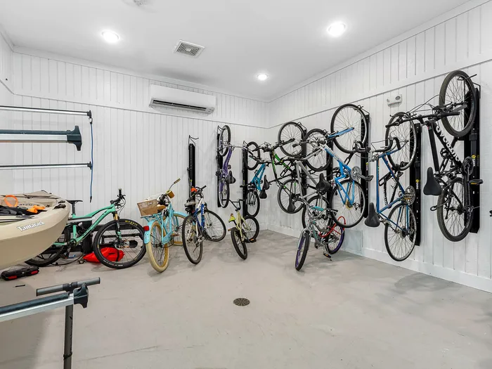 Bright and functional storage room showcasing multiple bicycles neatly hung on the wall, alongside a kayak, highlighting ample storage space in a modern apartment complex.