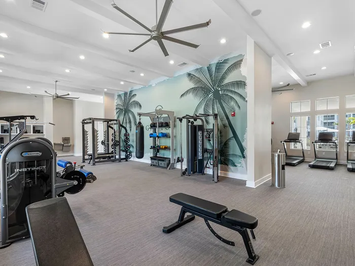 Modern apartment gym featuring state-of-the-art exercise equipment and a tropical palm mural for an energizing workout atmosphere.