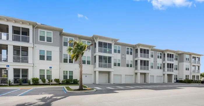 Modern apartment complex with stylish balconies and pristine facade under a clear blue sky, offering contemporary living in a serene environment.