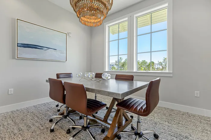 Chic modern dining room with elegant chandelier and large windows, featuring a stylish table and leather chairs, perfect for entertaining.