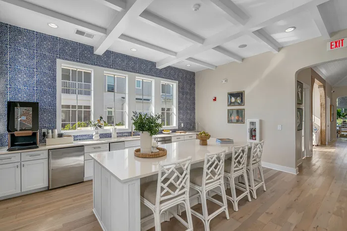 Bright and airy kitchen with elegant blue tile backsplash, large island with seating, and stainless steel appliances, offering a modern and inviting atmosphere.