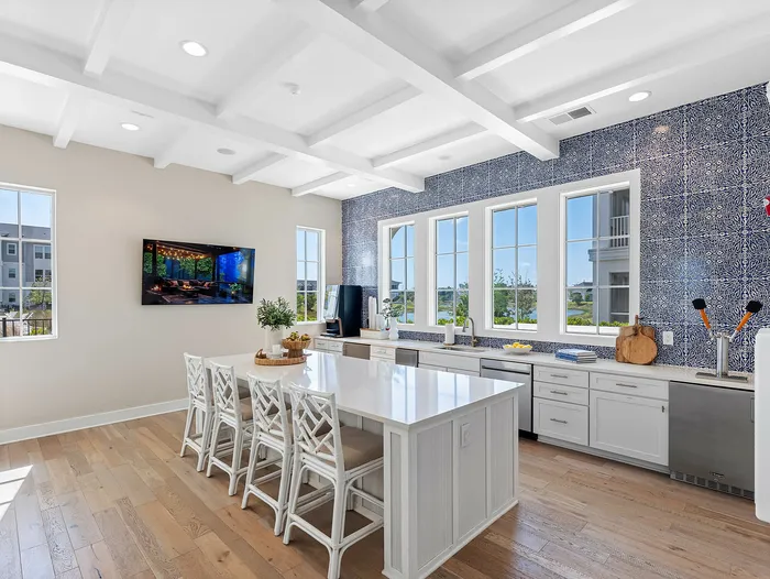 Bright and spacious kitchen with stylish blue patterned backsplash, large windows, and modern island seating.