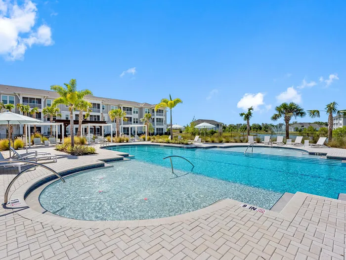 Luxurious apartment complex with a stunning outdoor pool, surrounded by lush palm trees and modern amenities, perfect for relaxation and leisure.
