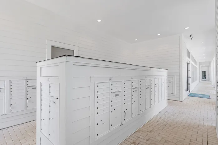 Chic and modern apartment mailroom featuring sleek white mailboxes and stylish overhead lighting.