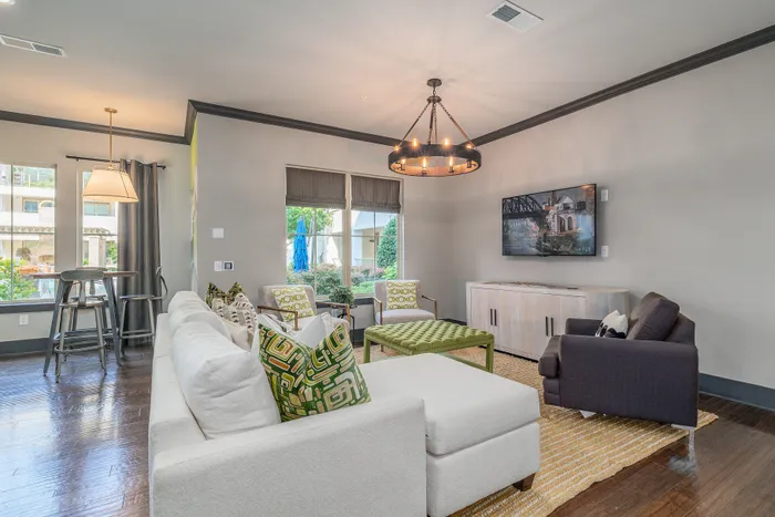Elegant living room with plush white sectional, modern chandelier, and large windows offering a scenic view.