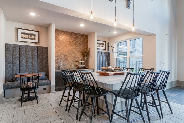 Elegant and modern dining area featuring a large marble table surrounded by stylish black chairs, under warm ambient lighting.
