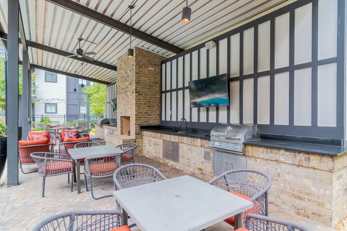 Chic outdoor living space with modern grill, brick fireplace, and cozy seating, ideal for entertaining.