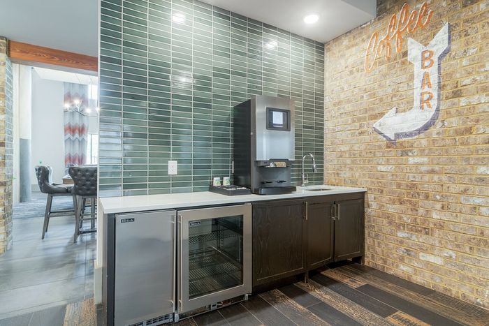 Chic apartment coffee bar with green tiled backsplash, modern espresso machine, and stylish cabinetry.