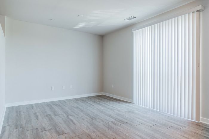 Bright and airy room with elegant light wood flooring and vertical blinds, perfect for a modern living space.
