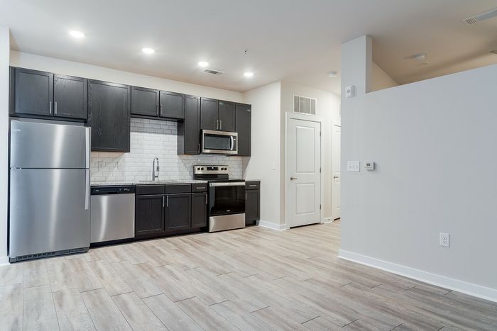 Modern kitchen design featuring sleek stainless steel appliances, dark wood cabinetry, and elegant tile flooring.