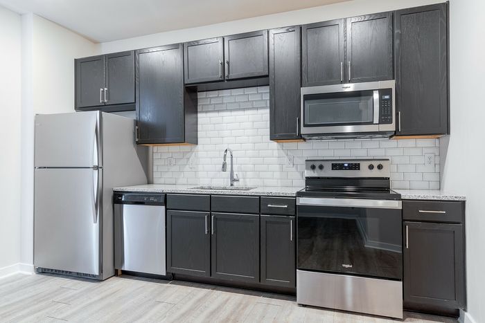 Modern kitchen with sleek stainless steel appliances, elegant dark cabinetry, and a stylish white subway tile backsplash.