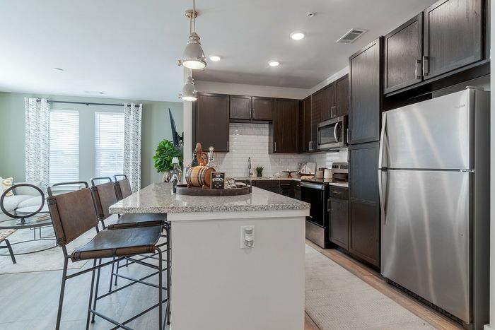 Modern kitchen with sleek dark cabinets, granite countertops, and stainless steel appliances, complemented by stylish pendant lighting and a spacious breakfast bar with chic seating.