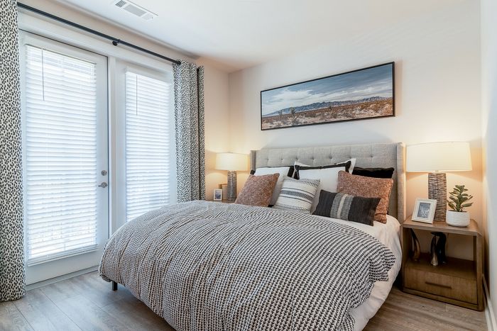 Inviting bedroom with a cozy bed, modern decor, and natural light streaming through elegant curtains.