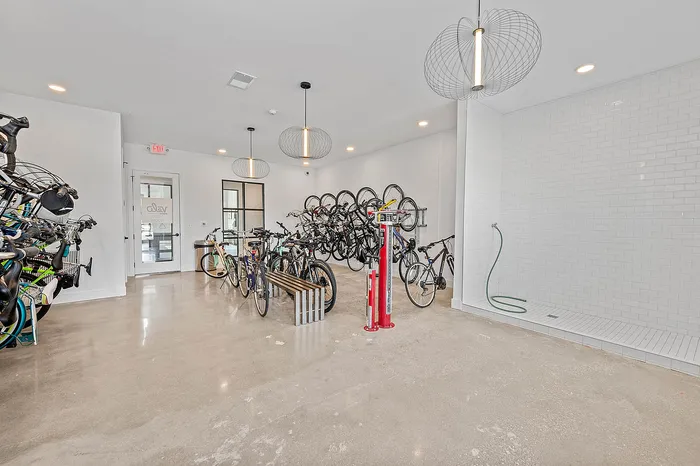 Modern bike storage room with ample space, stylish design, and convenient wash station, perfect for cycling enthusiasts.