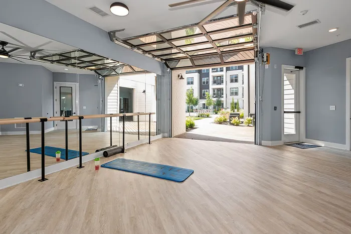 Bright and open exercise studio with mirrored walls and large windows with a view of landscaped outdoor area.