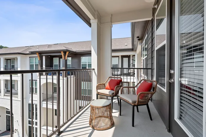 Charming apartment balcony with stylish wicker chairs and scenic courtyard view.