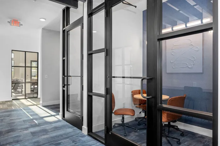 Modern office space featuring sleek glass doors and comfortable seating, perfect for productive meetings.