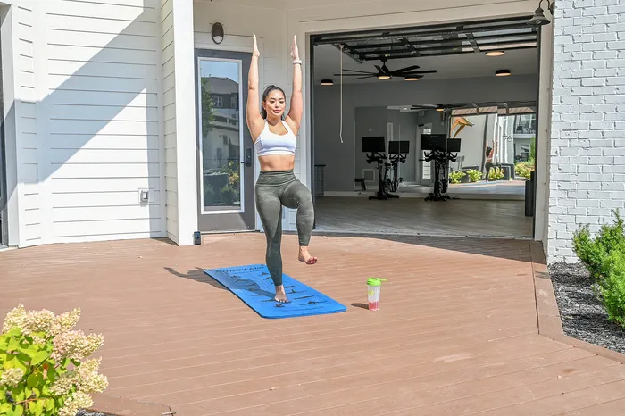Inviting outdoor fitness space with a yoga session in progress, adjacent to a modern gym with cycling equipment.