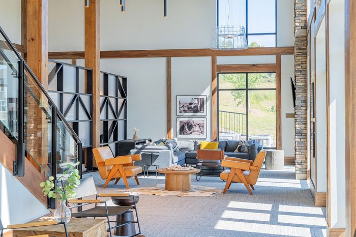 Bright and spacious open-concept living room with modern decor, featuring large windows, stylish wooden beams, and a cozy seating area.