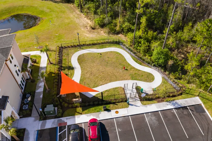 Vibrant aerial view of a landscaped park with winding paths, a bright orange shade sail, and lush greenery, perfect for relaxation and leisure.