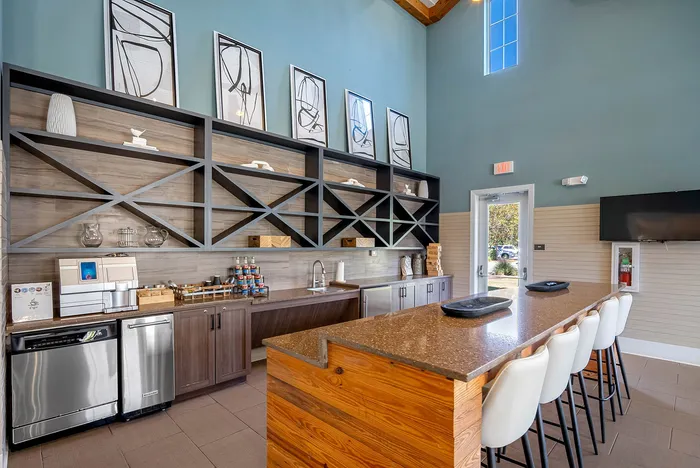 Contemporary kitchen with a sleek wooden bar countertop, stylish shelving, and ample natural light.