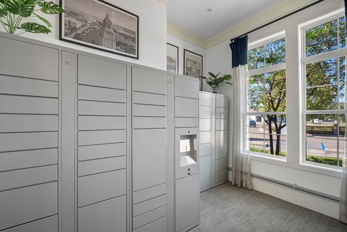 Modern package locker room with sleek gray lockers, large windows offering natural light, and stylish decor for a contemporary feel.