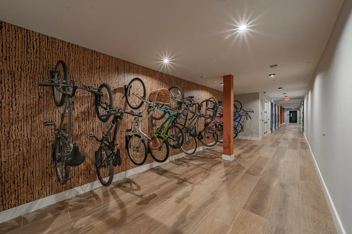 Modern apartment hallway featuring stylish wood flooring and convenient vertical bike storage.