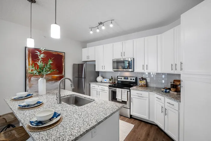 Modern kitchen with elegant granite countertops, sleek stainless steel appliances, and stylish white cabinetry, perfect for culinary enthusiasts.