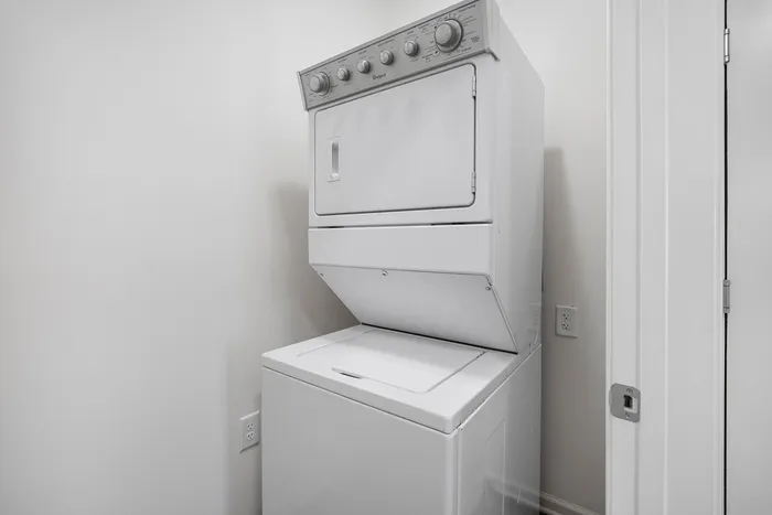 Convenient in-unit laundry area with a sleek, space-saving stacked washer and dryer set.