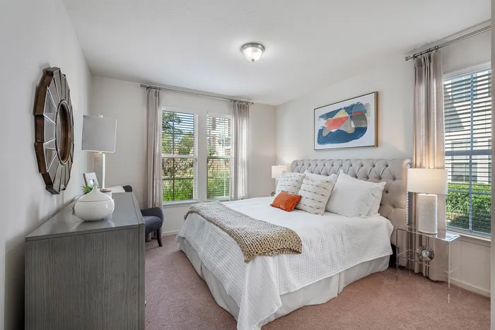 Bright and inviting bedroom with plush bedding, modern decor, and large windows offering lush garden views.