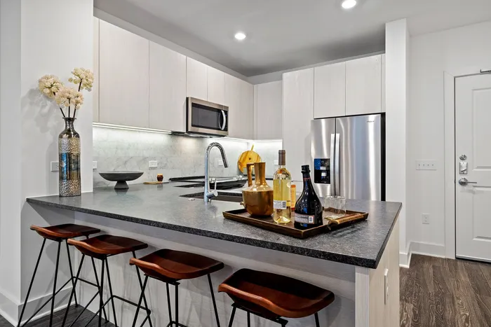 Elegant modern kitchen with sleek countertops, stainless steel appliances, and stylish bar stools, perfect for entertaining.