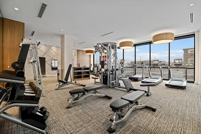 Modern fitness center with state-of-the-art gym equipment, sleek interiors, and large windows offering city views.