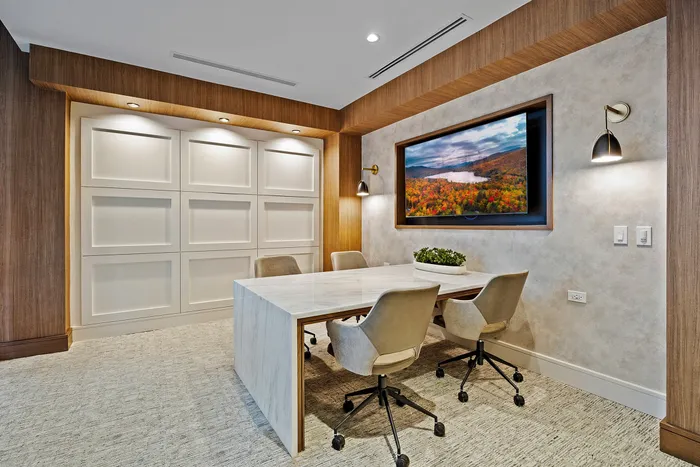 Modern meeting space featuring a sleek marble table, comfortable chairs, and inviting artwork on the wall, perfect for creativity and collaboration.