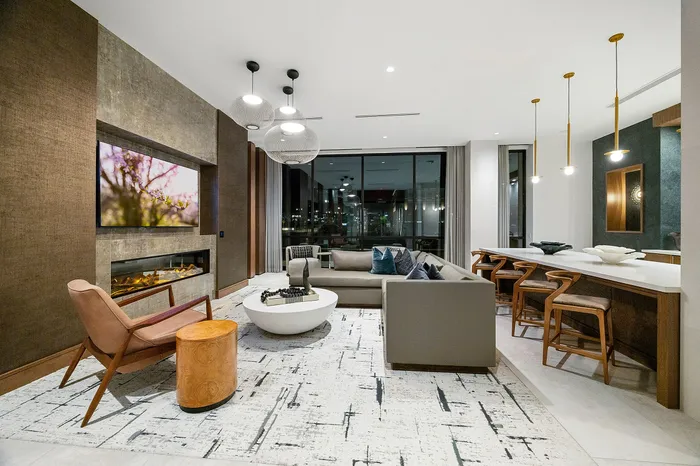 Elegant modern living space featuring a cozy fireplace, chic sectional sofa, and a stylish open-concept kitchen with sleek bar seating.