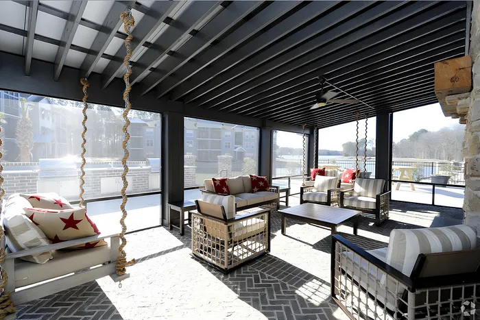 Charming screened-in porch with cozy outdoor seating, nautical-themed pillows, and scenic views, perfect for relaxation.