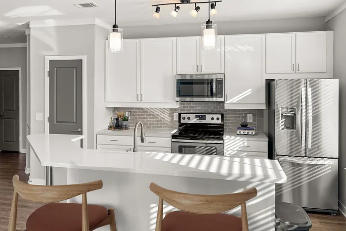 Modern kitchen with sleek stainless steel appliances, chic white cabinetry, and a cozy breakfast bar with stylish pendant lighting.