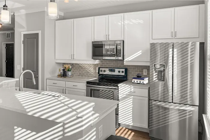 Bright and modern kitchen with sleek stainless-steel appliances, elegant white cabinetry, and chic pendant lighting for an inviting cooking space.