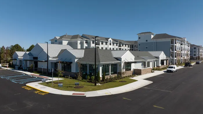 Modern apartment complex exterior showcasing sleek design, spacious sidewalks, and ample parking in a serene neighborhood setting.