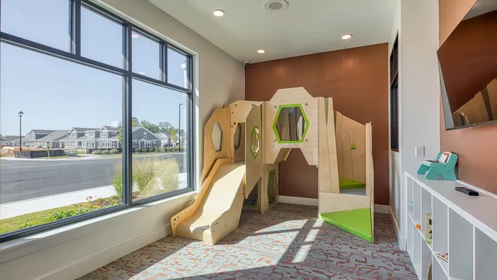 Bright playroom with modern wooden play structure, large windows offering natural light, and a view of the charming neighborhood.