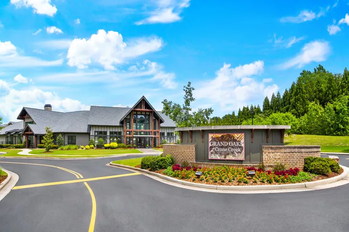 Elegant exterior of Grand Oaks at Crane Creek with lush landscaping and modern architecture under a vibrant blue sky.
